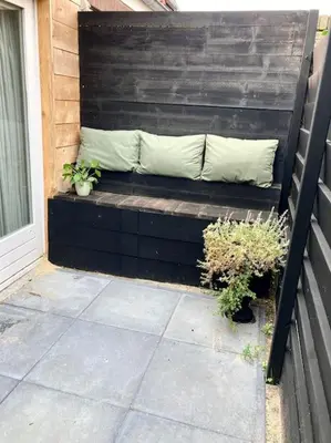 a wooden bench with two pillows and plants on it at Cosy beach house for ocean & nature lovers in Noordwijk