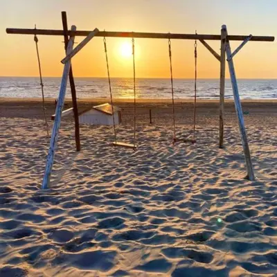 a swing set on the beach with the ocean in the background at Cosy beach house for ocean & nature lovers in Noordwijk