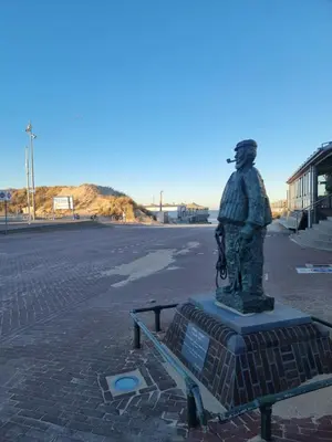 a statue of a man standing on a street at ZeeZuid in Egmond aan Zee