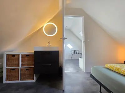 a attic bedroom with a sink and a mirror at ZeeZuid in Egmond aan Zee