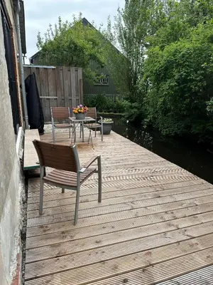 a wooden deck with two chairs and a table at Boutique appartement vlak bij Amsterdam in Rijnsaterwoude