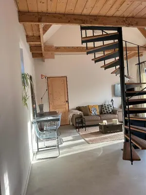 a living room with a couch and a spiral staircase at Boutique appartement vlak bij Amsterdam in Rijnsaterwoude