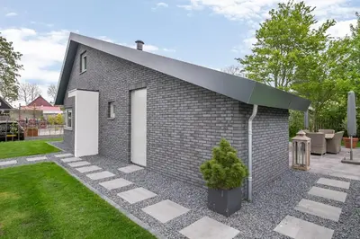 a small brick building with a green roof at VILLA ARYVE in See-, Strand- und Golfplatznähe inklusive NETFLIX, Bad en Suite und Wohlfühlgarantie in Dirkshorn