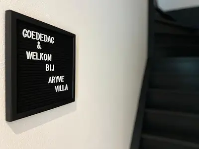 a picture of a sign on a wall next to a staircase at VILLA ARYVE in See-, Strand- und Golfplatznähe inklusive NETFLIX, Bad en Suite und Wohlfühlgarantie in Dirkshorn