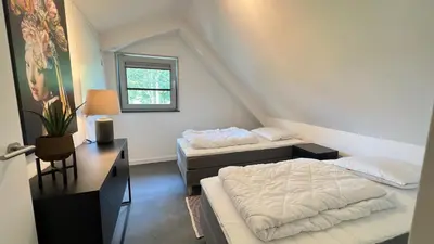 a bedroom with two beds and a desk and a window at VILLA ARYVE in See-, Strand- und Golfplatznähe inklusive NETFLIX, Bad en Suite und Wohlfühlgarantie in Dirkshorn