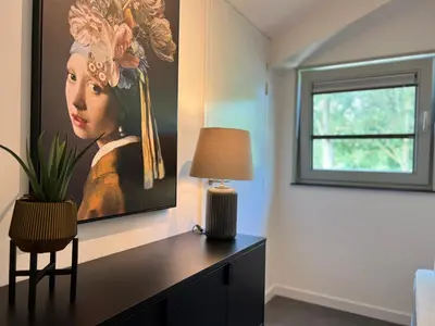 a bedroom with a painting of a woman with flowers on the wall at VILLA ARYVE in See-, Strand- und Golfplatznähe inklusive NETFLIX, Bad en Suite und Wohlfühlgarantie in Dirkshorn