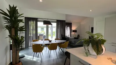 a kitchen and living room with a table and chairs at VILLA ARYVE in See-, Strand- und Golfplatznähe inklusive NETFLIX, Bad en Suite und Wohlfühlgarantie in Dirkshorn