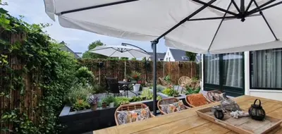 a patio with a wooden table and an umbrella at Bed and Breakfast Geliefd in Voorhout