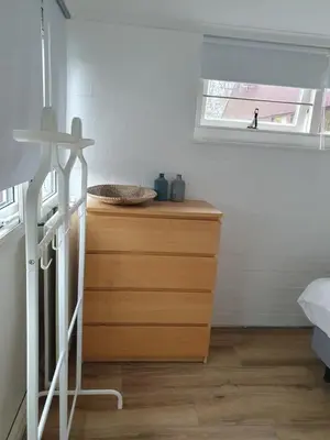 a bedroom with a wooden dresser and a window at Rekerlanden 117 in Schoorldam