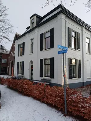 a white house with black windows and a street sign at De Oude Pastorie in Bunschoten