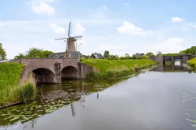 a mill and a river with a bridge and a windmill at B&B Hendricus in Hoofddorp