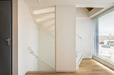 a staircase in a white room with a glass wall at Zon Modern beach house in Bergen aan Zee