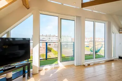 a living room with large windows and a flat screen tv at Zon Modern beach house in Bergen aan Zee
