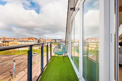 a chair on a balcony with a view of a street at Zon Modern beach house in Bergen aan Zee