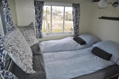 two beds in a small room with a window at The Cuckoo's nest in Amsterdam