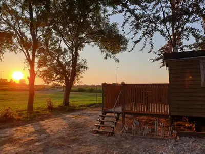 a gate to a cabin with the sunset in the background at The Cuckoo's nest in Amsterdam