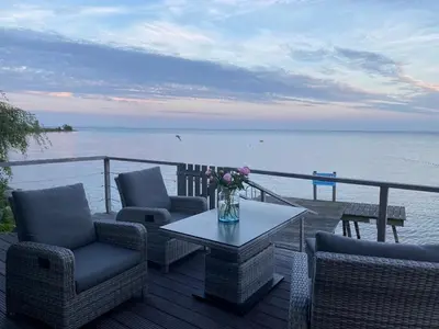 a patio with chairs and a table with a view of the water at Seaside in Bovenkarspel