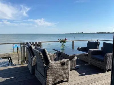 a deck with chairs and a table on the beach at Seaside in Bovenkarspel