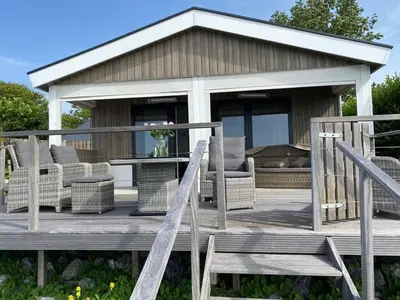 a wooden deck with wicker chairs and a pavilion at Seaside in Bovenkarspel