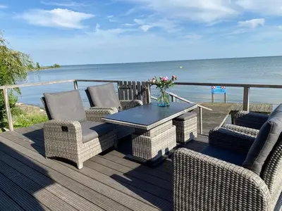 a deck with chairs and a table and the ocean at Seaside in Bovenkarspel