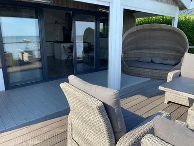 a covered deck with chairs and a couch and a table at Seaside in Bovenkarspel