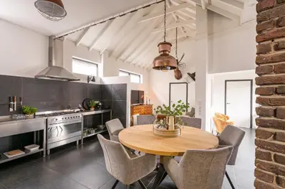 a kitchen and dining room with a wooden table and chairs at Villa La Chatelaine in Egmond aan Zee