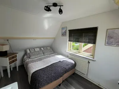 a small bedroom with a bed and a window at Heerlijk Huisje in Bergen in Bergen