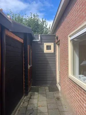 a black garage door next to a brick building at Heerlijk Huisje in Bergen in Bergen