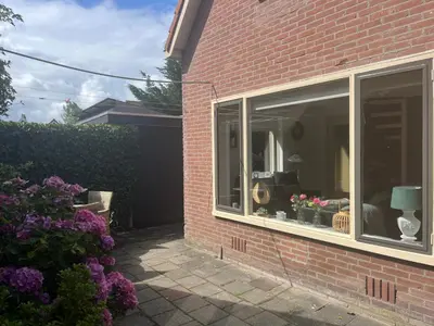a window of a house with flowers in it at Heerlijk Huisje in Bergen in Bergen