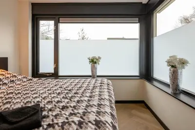 a bedroom with a bed and two windows at Luxe Studio Liemers in Lelystad