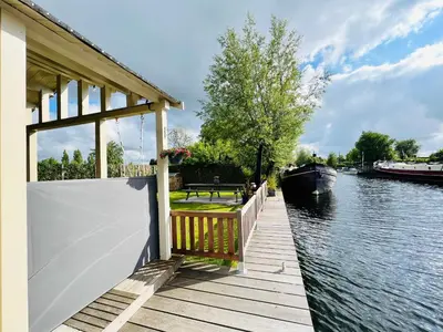 a wooden dock with a boat on the water at NEW - Private Cabin - on a lake near Amsterdam in Vinkeveen