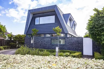 a black house with a gambrel roof at Villa Duinzand in Egmond aan den Hoef