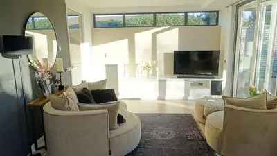 a living room with two chairs and a flat screen tv at Villa Duinzand in Egmond aan den Hoef