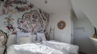 a bedroom with a bed with white sheets and a wallpaper at Villa Duinzand in Egmond aan den Hoef