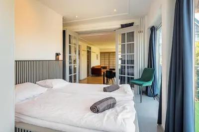 a bedroom with a white bed and a green chair at Wind - Modern beach house in Bergen aan Zee