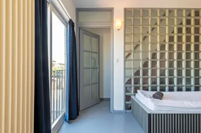 a room with a bed and a window and a balcony at Wind - Modern beach house in Bergen aan Zee