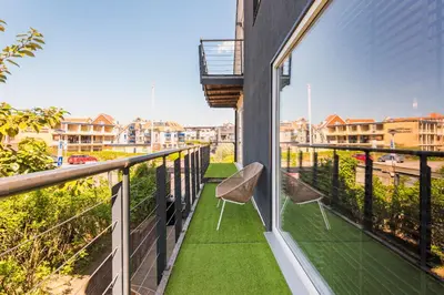 a balcony with two chairs and green grass at Wind - Modern beach house in Bergen aan Zee