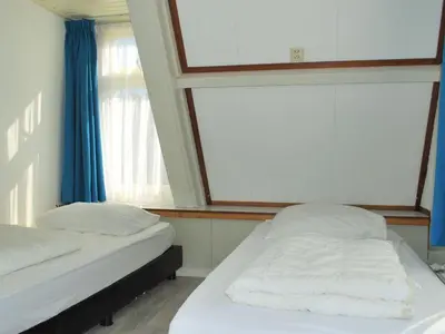 two beds in a room with a large window at Vakantiehuis Seahorse in Egmond aan Zee