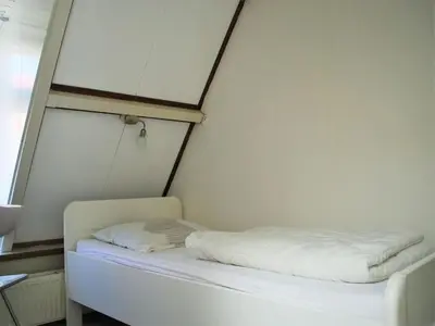 a small room with a bed with white sheets at Vakantiehuis Seahorse in Egmond aan Zee