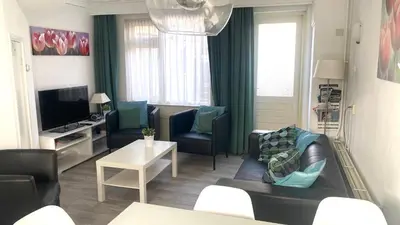a living room with a couch and chairs and a tv at Vakantiehuis Seahorse in Egmond aan Zee