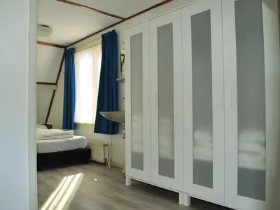 a room with a bedroom with a bed and blue curtains at Vakantiehuis Seahorse in Egmond aan Zee