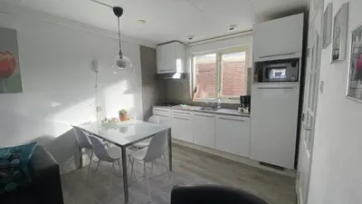 a kitchen with white cabinets and a table with chairs at Vakantiehuis Seahorse in Egmond aan Zee