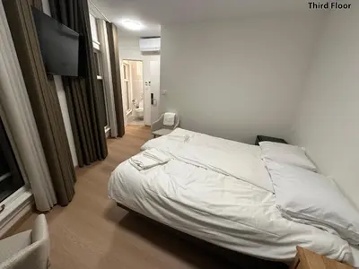 a bedroom with a white bed and a flat screen tv at Voyagers Amsterdam in Amsterdam