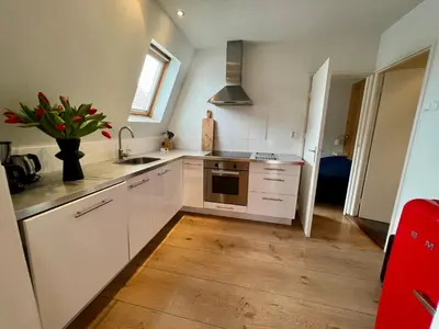 a kitchen with white cabinets and a vase of flowers at Vakantiehuis Achter de Duinen in Castricum