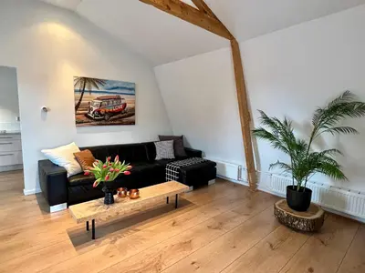 a living room with a black couch and a table at Vakantiehuis Achter de Duinen in Castricum