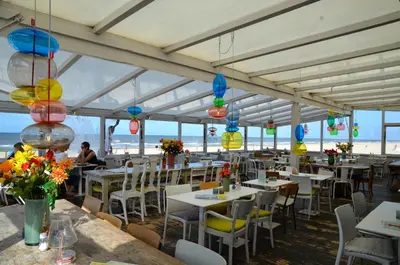 a restaurant on the beach with tables and chairs at Vakantiehuis Achter de Duinen in Castricum