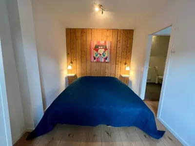 a bedroom with a blue bed and a painting on the wall at Vakantiehuis Achter de Duinen in Castricum