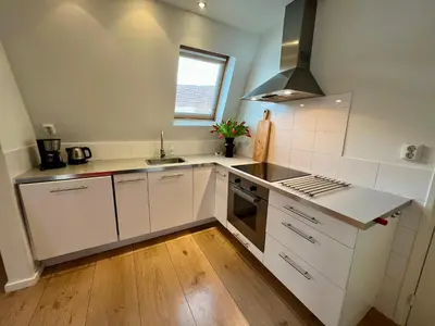 a white kitchen with a sink and a stove at Vakantiehuis Achter de Duinen in Castricum