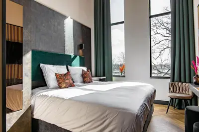 a bedroom with a large bed and a large window at Monument Hotel in Zaandam