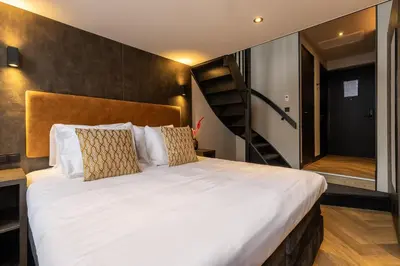 a bedroom with a large bed and a staircase at Monument Hotel in Zaandam